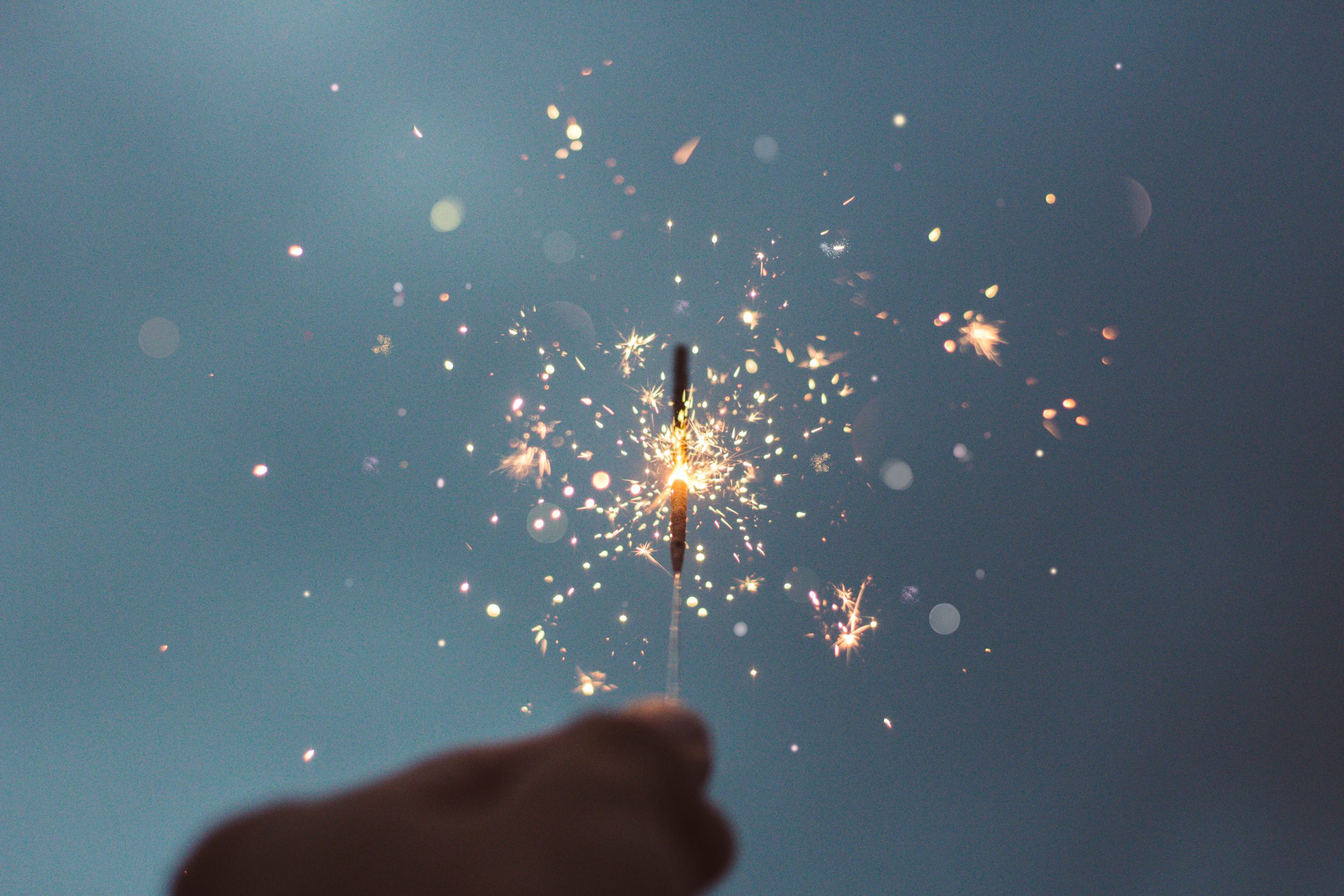 hand holding a lit sparkler with dark blue background